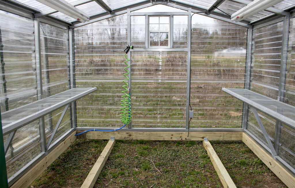 clear greenhouse for plants with hose, shelves, and window